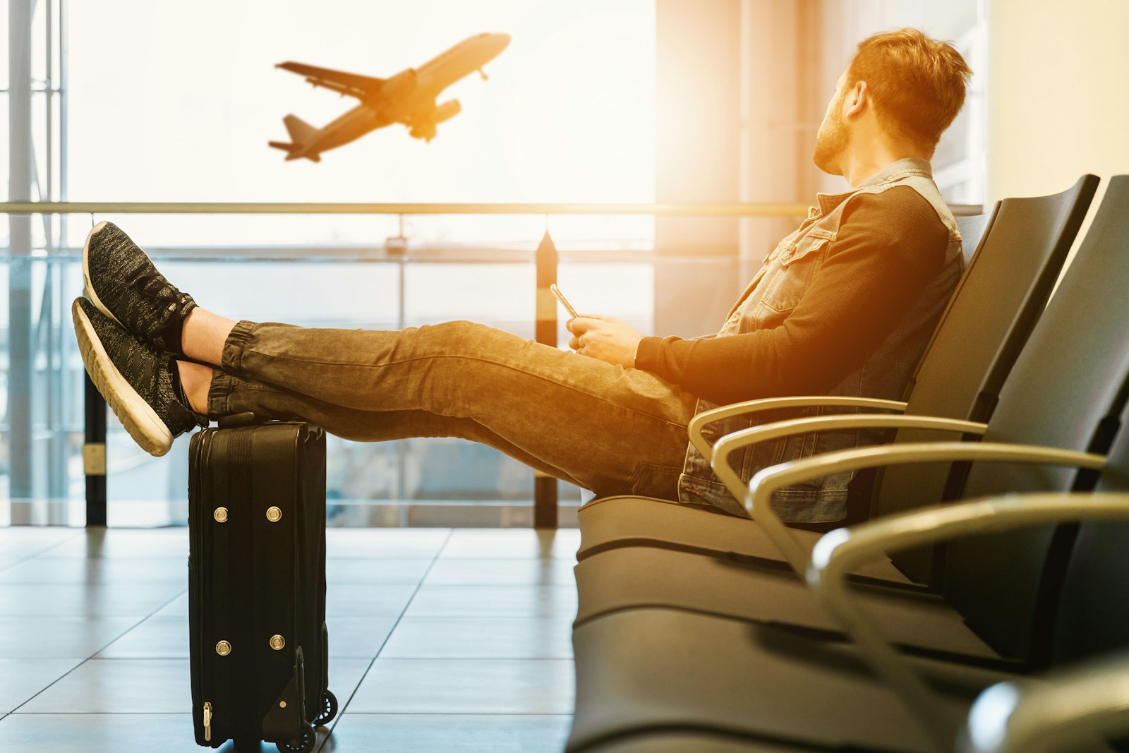 Traveler waiting beside airport seating with an airplane outside the window